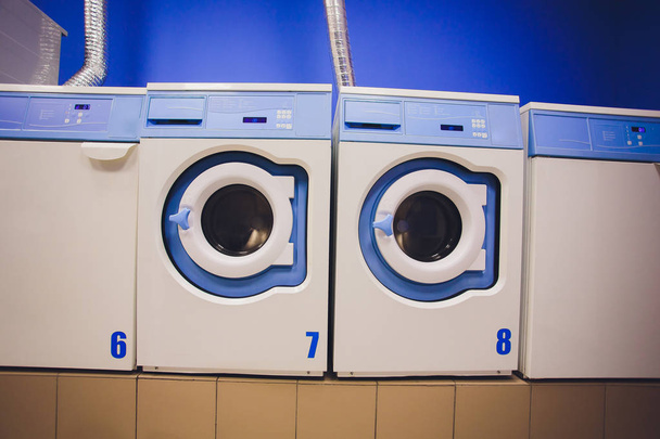 Professional washing machines with baskets full of clothes at the self-service laundry. - Фото, зображення