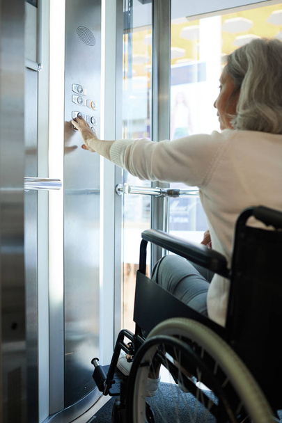 Mozgáskorlátozott idős nő ül tolószékben a liftben - Fotó, kép