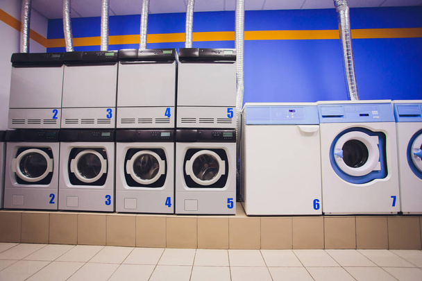 Professional washing machines with baskets full of clothes at the self-service laundry. - 写真・画像
