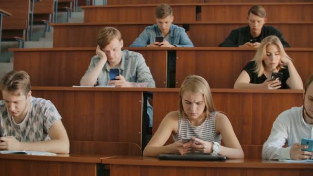 multiethnische Gruppe von Studenten, die während der Vorlesung Smartphones benutzen. Junge Menschen nutzen soziale Medien während ihres Studiums. - Filmmaterial, Video