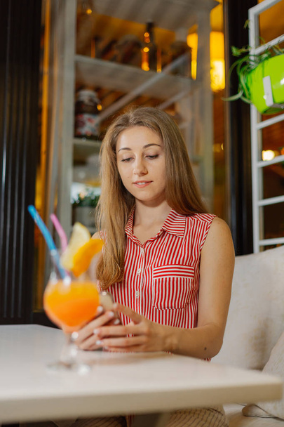 Belle fille avec un cocktail frais lumineux dans un café
. - Photo, image