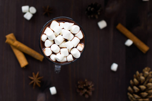 chocolate caliente y mini malvavisco con decoraciones de invierno sobre fondo negro vista superior
 - Foto, Imagen