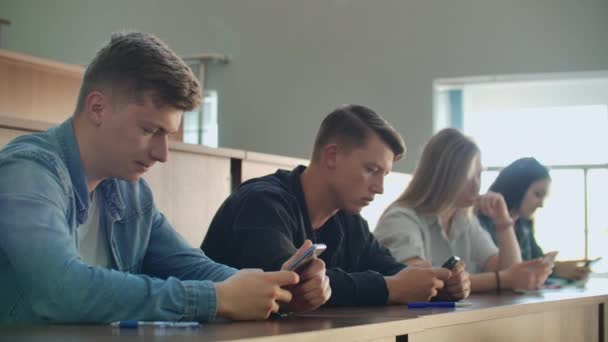 Grupo Multi Étnico de Estudiantes Usando Smartphones Durante la Conferencia. Jóvenes usando las redes sociales mientras estudian en la Universidad
. - Metraje, vídeo