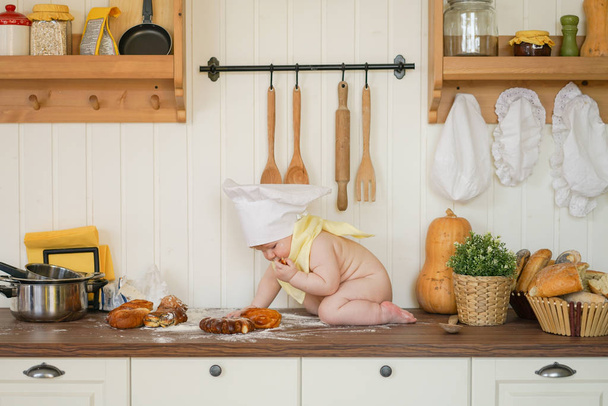 little baker child in chef hat at kitchen table alone - Photo, Image