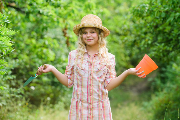 帽子をかぶった小さな女の子の農夫。農業と農業。春の田舎側の村。夏。ポットとシャベルを持つ小さな女の子。地球の日。環境生態学。自然保護。ガーデニングツール - 写真・画像