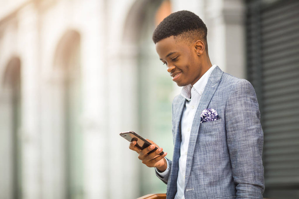 handsome young african man in a suit with a phone in his hand - 写真・画像