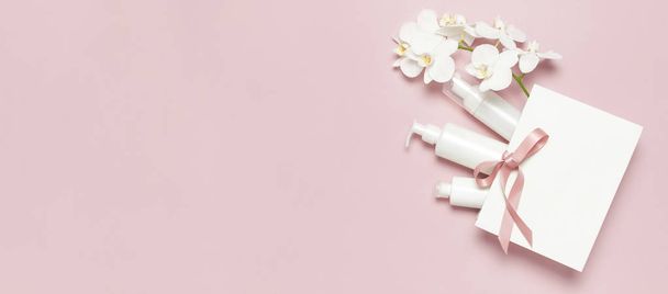 Lakás feküdt fehér kozmetikai palack konténerek ajándék táska fehér Phalaenopsis orchidea virágok rózsaszín háttér felső nézetben. Kozmetika Spa branding modell-természetes szerves kozmetikai termék koncepció minimalizmus stílus - Fotó, kép