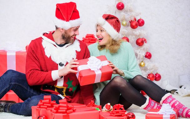 Loving couple cuddle smiling while unpacking gift christmas tree background. Gift to beloved. Couple in love happy enjoy christmas holiday celebration with gifts. Family prepared christmas gifts - Foto, immagini
