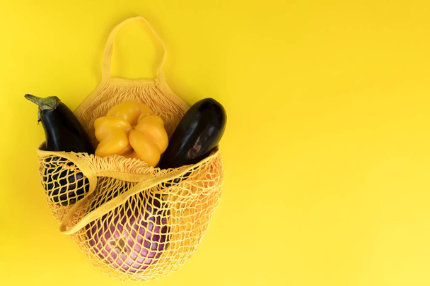 新鮮な野菜、庭の食材、きれいな食事とダイエットの概念。黄色の背景にネットコットンバッグの野菜 - 写真・画像