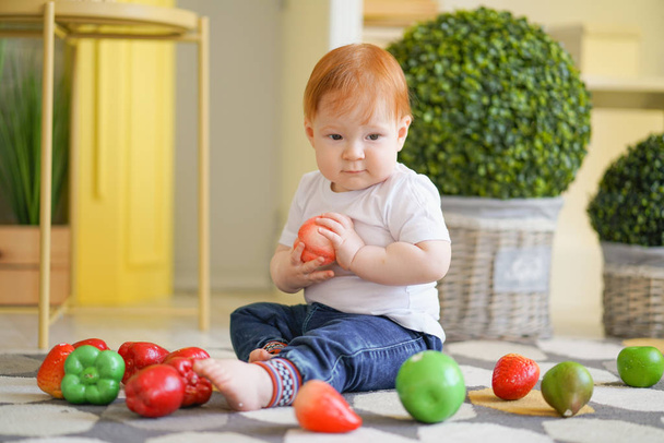 kırmızı saçlı tombul çocuk sebze ile oynar - Fotoğraf, Görsel