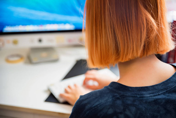 Просмотр рыжеволосая девочка-подросток учится на компьютере в своей комнате
 - Фото, изображение