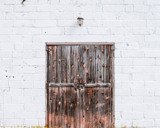 Old wooden gate in a white brick wall. Lantern over the door. - Fotoğraf, Görsel