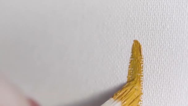 Close up for the woman hand holding a brush and painting on white canvas, oil painting and art concept. Action. Female artist drawing the line of mustard color. - Filmagem, Vídeo