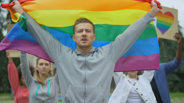 Fešák s duhovou vlajkou uprostřed demonstrantů za práva gayů, Lgbt Pýcha akce - Záběry, video