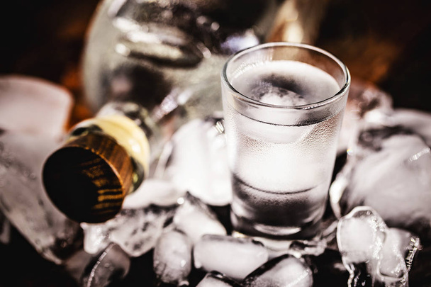 Vodka in bicchierini su fondo rustico in legno e ghiaccio
 - Foto, immagini