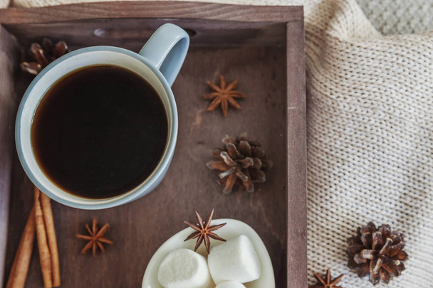 Kopje koffie op rustieke houten dienblad, zoete marshmallow en warme wollen trui - Foto, afbeelding