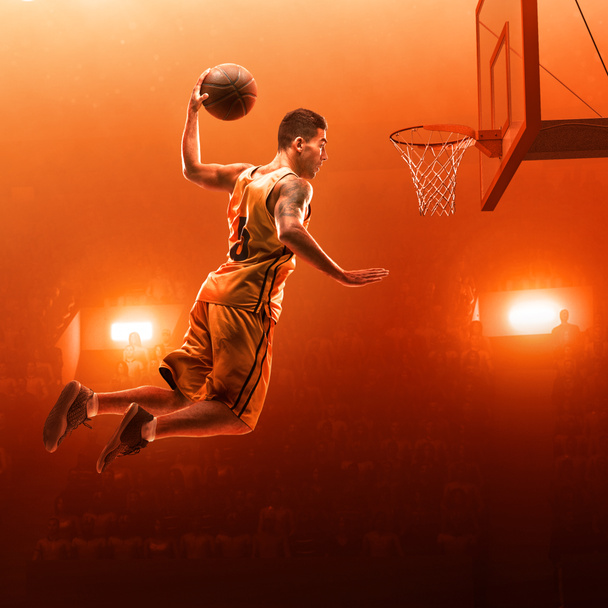 Jugador de baloncesto cerca del aro con la pelota. Golpe de clavo. Fondo rojo iluminado por las inundaciones
 - Foto, imagen