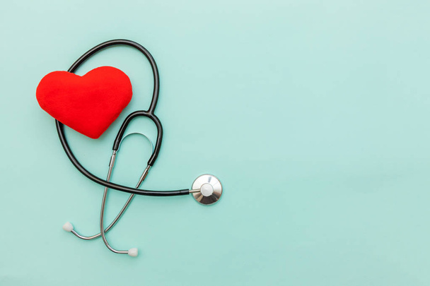 Medicine equipment stethoscope or phonendoscope and red heart isolated on trendy pastel blue background. Instrument device for doctor. Health care life insurance concept - 写真・画像