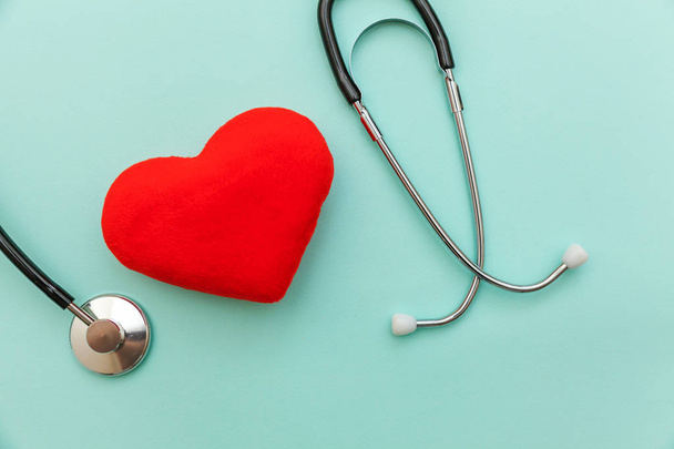 トレンディなパステルブルーの背景に隔離された医療機器聴診器や音声鏡と赤い心臓。医師のための器械装置。医療保険の概念 - 写真・画像