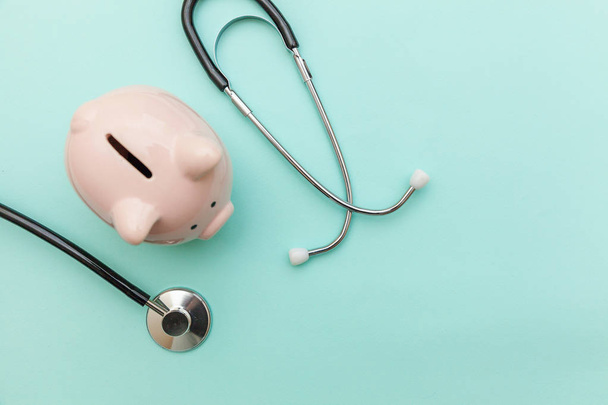 Medicine doctor equipment stethoscope or phonendoscope and piggy bank isolated on trendy pastel blue background - Foto, imagen