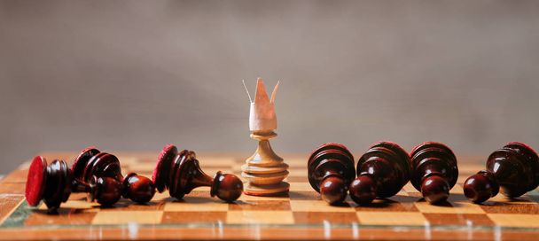 King or boss, leadership and business strategy. Board game. A pawn with a crown in the middle of the losing pieces - Photo, Image