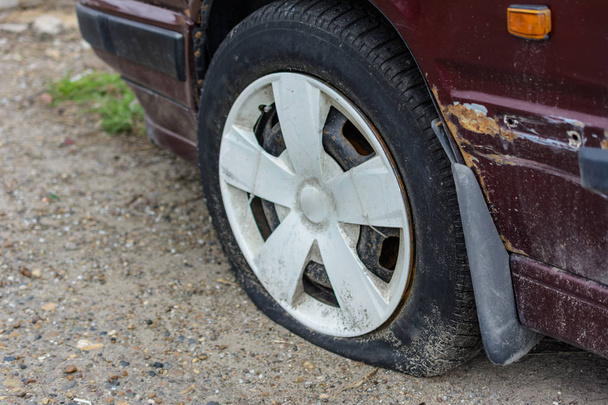 Damaged tire. The wheel of car tire leak. Flat tire on the off-r - Photo, Image