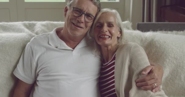 Portrait of a senior Caucasian woman and man sitting on a couch and smiling - Filmagem, Vídeo