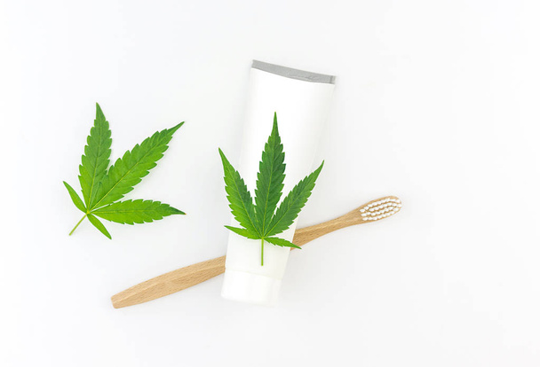 Pasta de dientes CBD de cannabis con hojas de cannabis y cepillo de dientes de madera
 - Foto, imagen