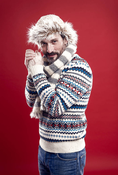 Enduring cold. A winter ensemble protects him from cold. Bearded man accessorizing sweater with hat and scarf. Mature fashion model enjoys cold weather style. Winter wardrobe for man, vintage filter - Фото, изображение