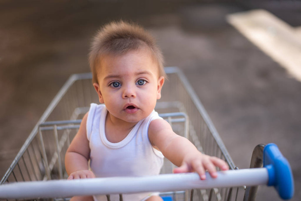 Голубоглазый ребенок в тележке супермаркета
 - Фото, изображение