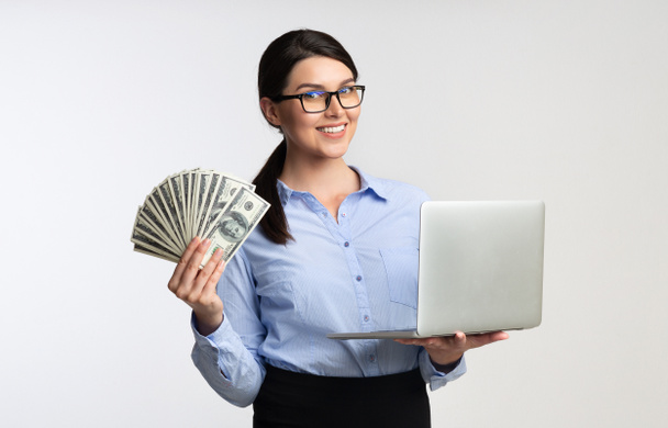 Business meisje houdt laptop computer en geld op witte achtergrond - Foto, afbeelding