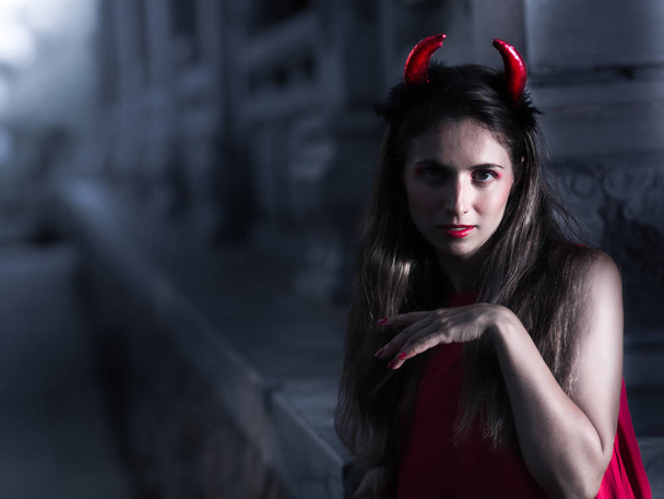 Beautiful woman in red dress and horns. Halloween - Zdjęcie, obraz