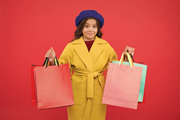 Obsessed with shopping. Girl cute kid hold shopping bags red background. Get discount shopping on birthday holiday. Fashionista adore shopping. Customer satisfaction. Prime time buy spring clothing - Photo, Image