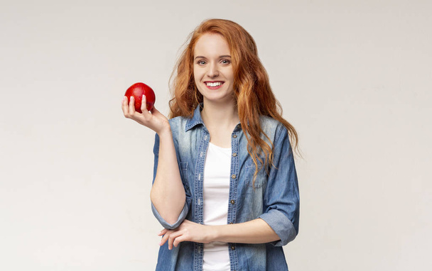 Portrét usmívající se dívky se zdravými zuby s červeným jablkem - Fotografie, Obrázek