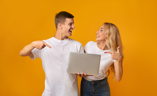 Jeunes gens joyeux pointant vers ordinateur portable dans leurs mains
 - Photo, image