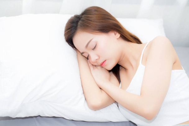 Όμορφη Ασιατική νεαρή γυναίκα κοιμάται ξαπλωμένη στο κρεβάτι με το κεφάλι σε p - Φωτογραφία, εικόνα