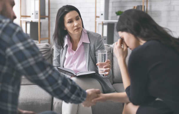 Worried psychologist offering glass of water for woman to calm down - Photo, Image