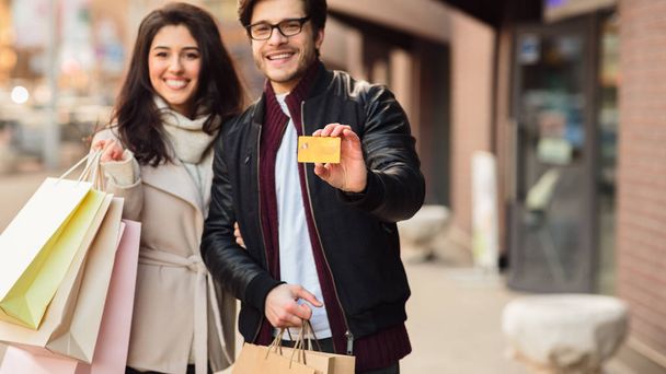 Feliz hombre mostrando tarjeta de crédito después de ir de compras con su esposa
 - Foto, imagen