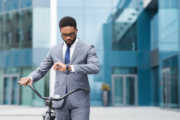 Empresário afro confiante olhando para seu relógio, indo para casa
 - Foto, Imagem