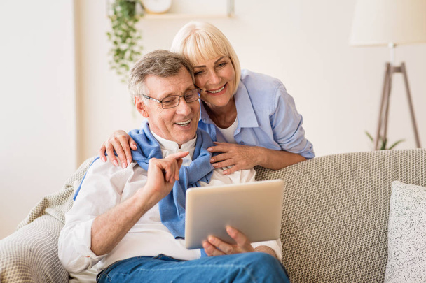 Щасливі пенсіонери використовують планшет, розслабляючись на килимі
 - Фото, зображення