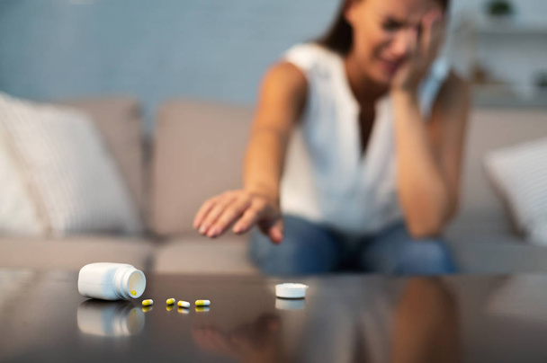 Suicidal Girl Reaching After Antidepressant Pills Sitting On Couch Indoor - Photo, Image