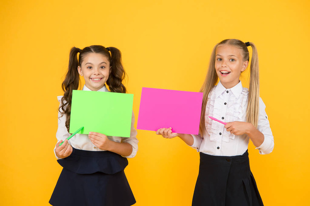 Important lesson you should learn. Cute small children reciting lesson with pen and paper on yellow background. Little girls having lesson in writing. Using exciting ideas in the lesson, copy space - Foto, afbeelding