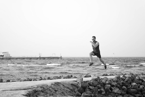 athlete runner along sea coast. running to success. summer vacation. copy space. speed concept. goal and future. people and nature. man runner focused on achievement. life as marathon or sprint - Fotó, kép