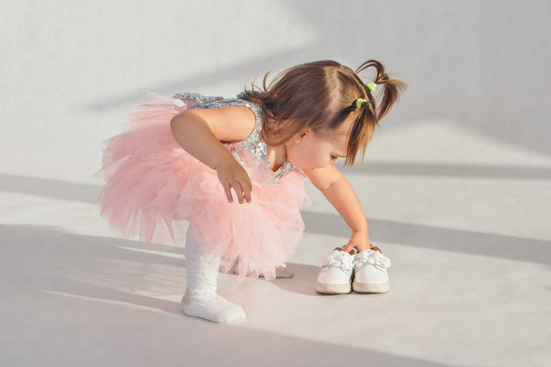 clothing advertising: little girl beautifully puts shoes on the floor on a white background - Foto, Imagem