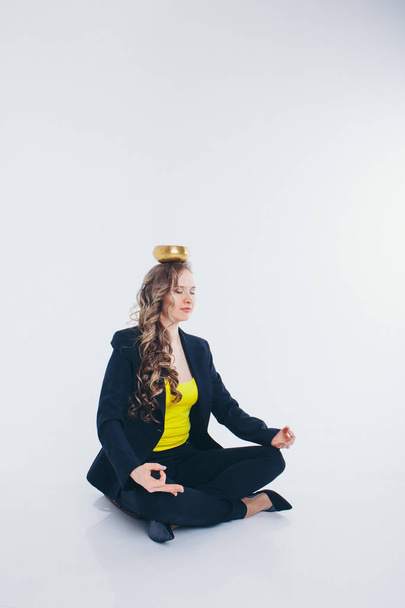 businesswoman meditating. Preparation of a potion on a white background. Singing bowl with Buddhist mantra in woman's hand in a suit - Foto, Imagen