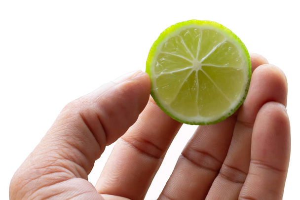 Egy férfi keze vesz egy szelet organikus friss zöld citrom fehér háttér - Fotó, kép