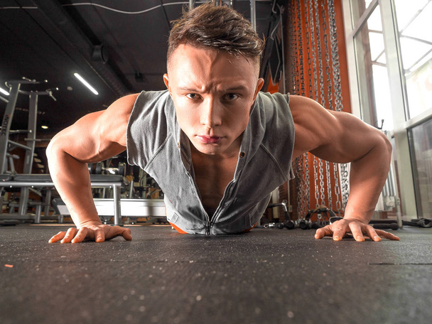 Close up photo of a fitness man doing push ups in gym. - Photo, Image