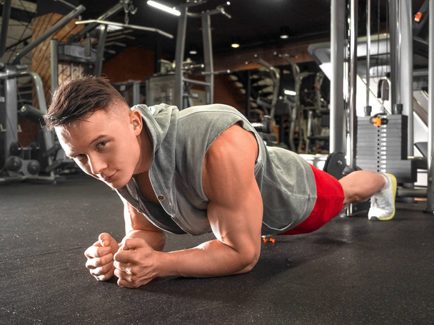 Man workout in Fitness Club. Portret van blanke man maken elleboog plank oefening. - Foto, afbeelding