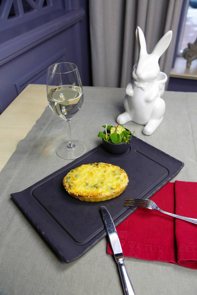 Tarta de quiche con una copa de vino blanco sobre una mesa en un restaurante
 - Foto, Imagen