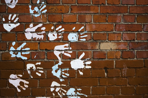 Texture of a red brick wall with imprint of a person. many White prints of the palms of the hands on the brick wall. a lot handprints - Foto, Imagem